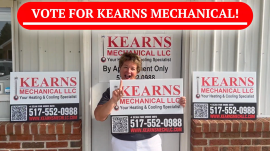Photo of General Manager Diane Kearns holding up Kearns Mechanical signs with #1 finger