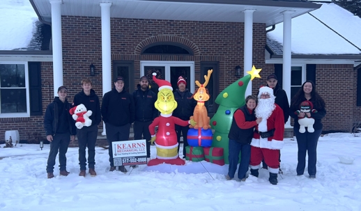 The Kearns Mechanical Team standing around a Christmas Grinch blowup