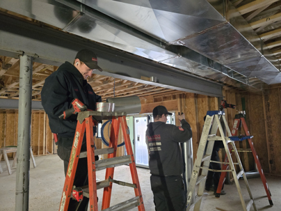 Two Kearns Mechanical technicians working on a project in a basement.